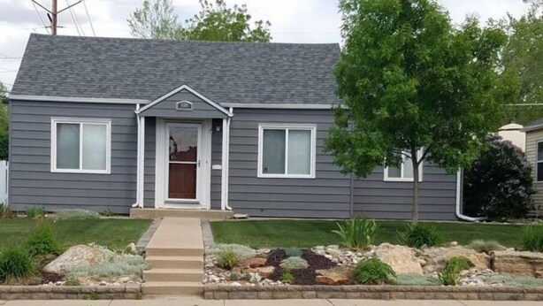 A two-story house with a front porch, a garage, and a well-maintained lawn with a rock garden.