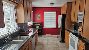A kitchen with wooden cabinets, a stainless steel sink, a refrigerator, and a stove.