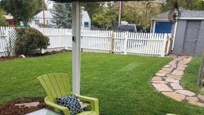 A patio area with green chairs and a patterned rug.