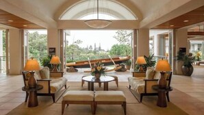 A spacious lobby with a large arched ceiling, comfortable seating areas, and a view of a boat through large windows. - Wyndham Bali Hai 3BR Suite with Resort Access (Princeville)