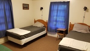 A room with two single beds, a small table, and a chair. - Hawthorne Cottages Chickadee Heights (Raymond)