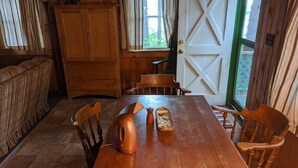 A wooden dining table with six chairs, a copper kettle, and a tray with food items.