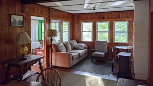 A cozy cabin interior with a wooden interior, a sofa, a dining table, and a lamp. - Hawthorne Cottages Edgewater (Raymond)