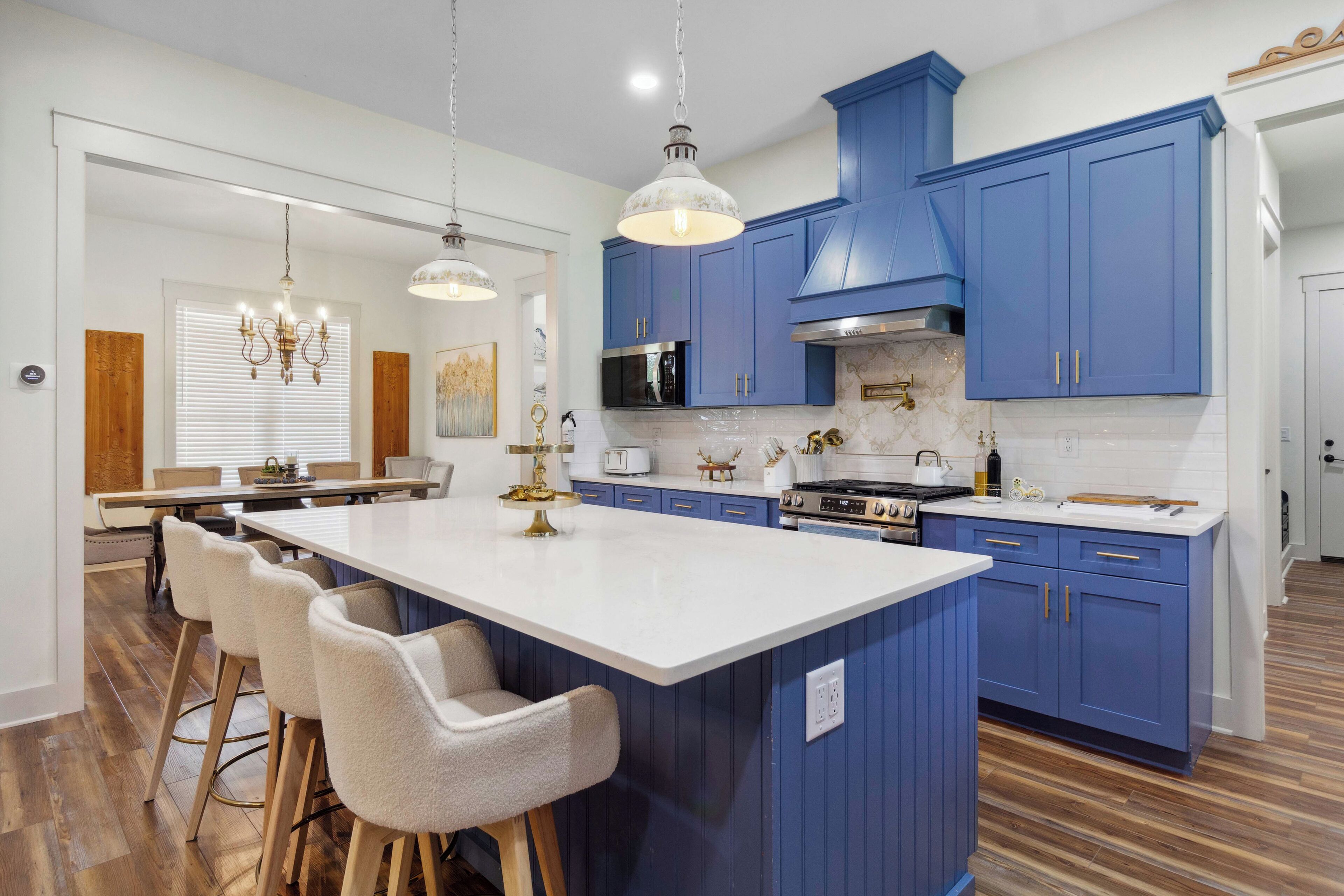 A modern kitchen with blue cabinets, a white island, and bar stools.