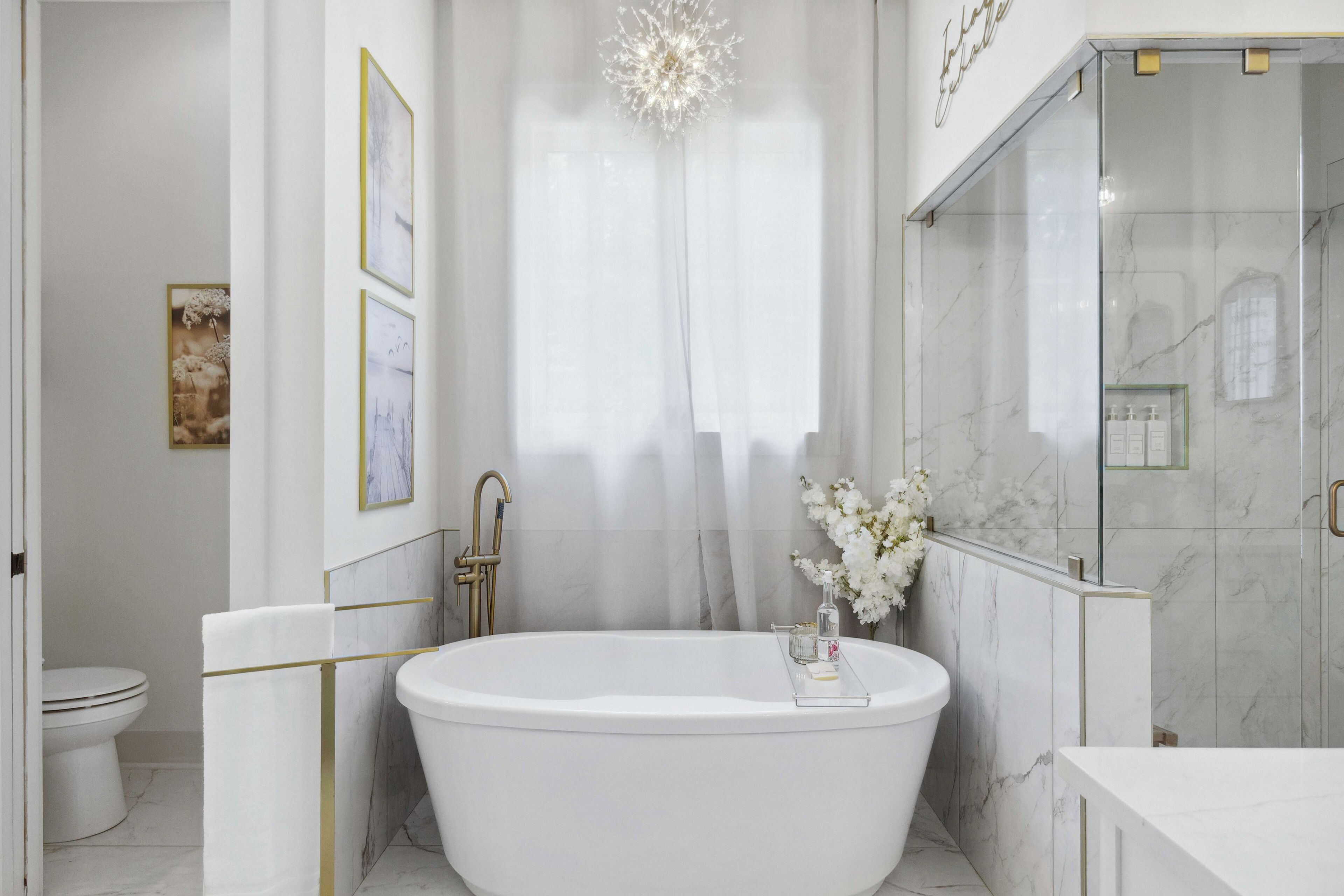 Ein modernes Badezimmer mit freistehender Badewanne, einer Duschkabine aus Glas und Marmorwänden.