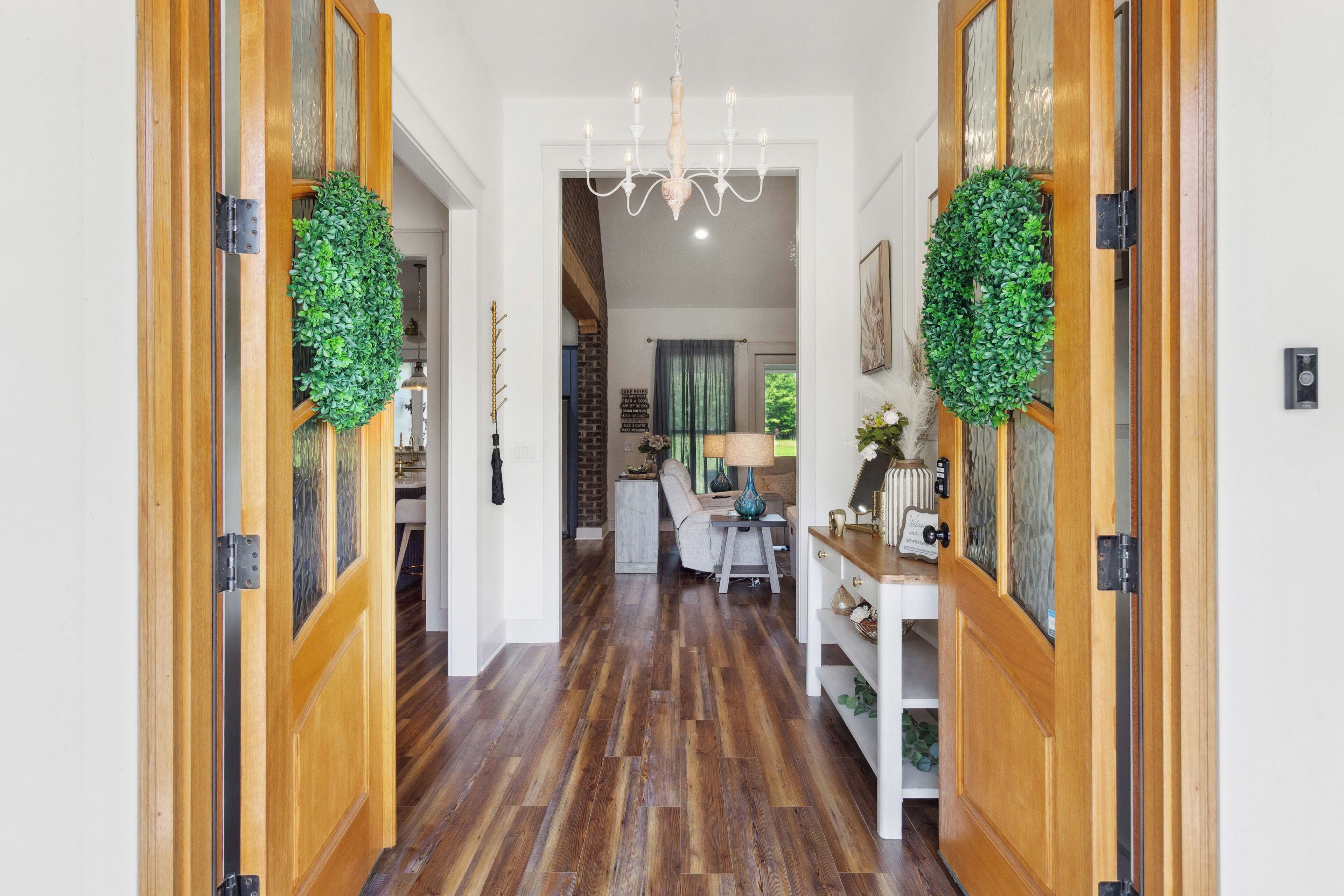 Un couloir doté de parquets en bois, d’un lustre et de deux portes ornées de guirlandes vertes.