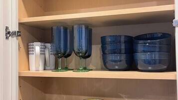 A cabinet with shelves containing stacked plates and blue glassware.