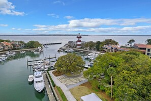A marina with boats docked, a lighthouse, and a tree-lined waterfront.
