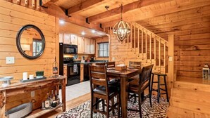 A wooden interior with a dining area, kitchen, and staircase.