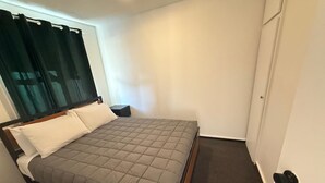 A single bed with a grey quilt, a wooden headboard, and a white wall. - 301 Bealey Ave Motel (Christchurch)