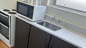 A kitchen with a microwave, stove, sink, and dark cabinets. - 301 Bealey Ave Motel (Christchurch)