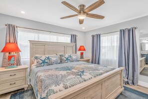 Ein Schlafzimmer mit einem Bett, zwei Nachttischen, einem Deckenventilator und einem Schminkspiegel.