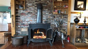 A rustic room with a brick fireplace, shelves with various items, and a wooden floor. - Maison de LaMontagne: Unique hill top home with stunning views in Corinth (Corinth)
