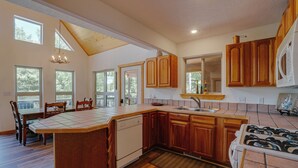 A spacious kitchen with wooden cabinets, a large island, and a view of the outdoors. - Home with a Mountain View above the Angel Fire Golf Course (Angel Fire)