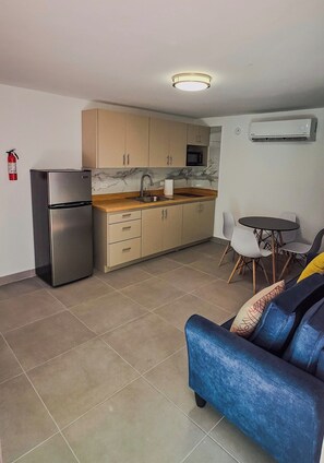 A compact living space with a kitchenette, a sofa, and a dining area.