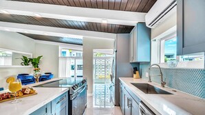 Cozinha moderna com ilha central, eletrodomésticos de aço inoxidável e vista para o exterior.