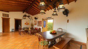 Un comedor amplio con una gran mesa de madera, varias sillas y lámparas colgantes.