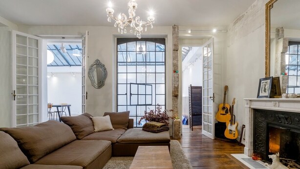 Una sala de estar con un sofá seccional marrón, una mesa de centro de madera, una chimenea y una guitarra.