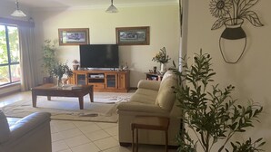 A living room with a sofa, a coffee table, a TV, and framed pictures on the wall. - Private mooring with access to the main river, just 75 metres away. (Renmark)