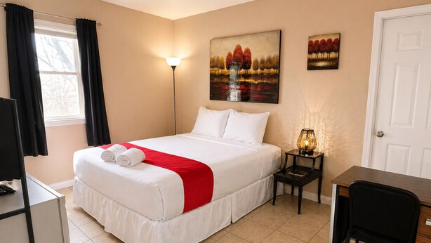 Ein Hotelzimmer mit Bett, Schreibtisch, Stuhl, Lampe und Bildern an der Wand.