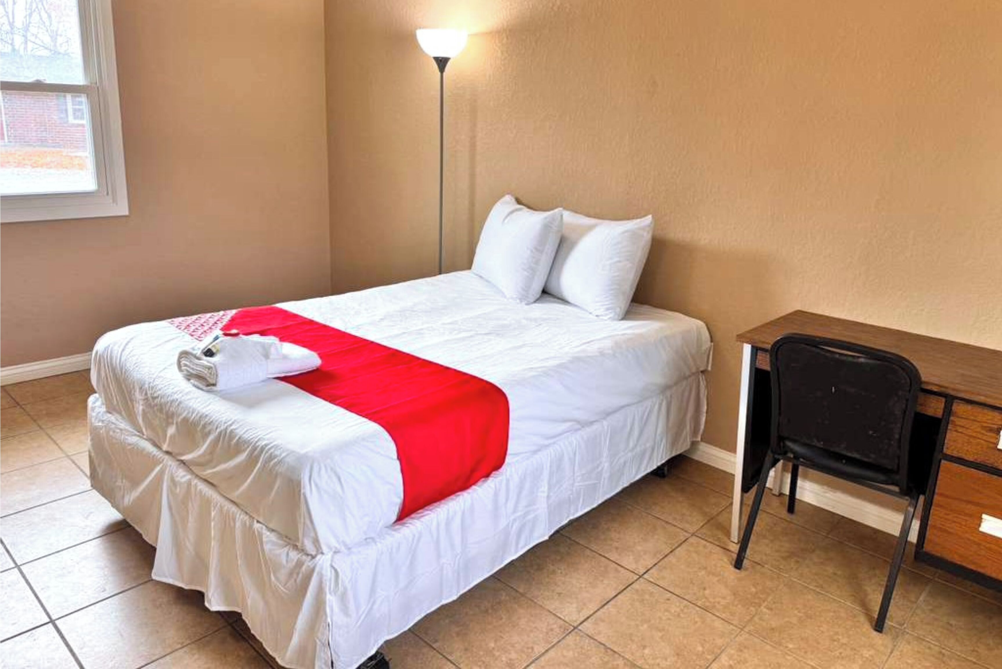 A hotel room with a bed, a desk, and a chair.