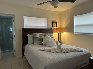 Relax in comfort with a neatly made bed, a glass shower, and a ceiling fan.