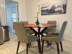 Enjoy meals in this stylish dining area with a round table, four comfortable chairs, and a beautiful wave-inspired painting.