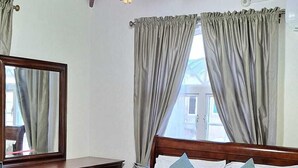 Un dormitorio con cama de madera, ventilador de techo y cortinas.
