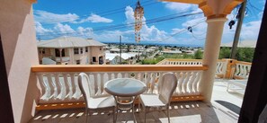Ein Balkon mit Tisch und Stühlen, der auf ein Wohngebiet mit Häusern und einem klaren Himmel blickt.