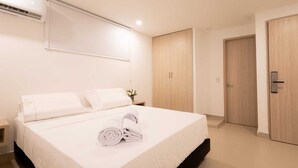 A modern hotel room with a neatly made bed, a wooden wardrobe, and a small bedside table with a vase of flowers.