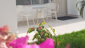 A building with a white exterior, a crown symbol above the name 'MISHKA', and a wreath on the door. There are white chairs outside and a potted plant to the right.