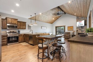 A spacious kitchen with wooden cabinets, a large island with bar stools, a stone accent wall, and a sign for Table Rock Resorts.