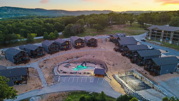 Et resort med flere hytter, en central pool og en parkeringsplads.