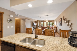 A kitchen with granite countertops, a double sink, and a coffee maker.