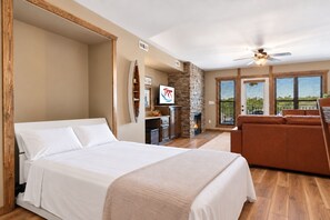 Un dormitorio amplio con una cama grande, chimenea y vistas al exterior.