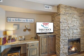 A stone fireplace with a TV mounted above it displaying 'Table Rock Resorts'. - Family-Friendly 2BR • Patios, Fireplaces, Pools & Lake Resort Fun (Branson)