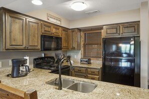 Una cocina con armarios de madera, un refrigerador de acero inoxidable, una cafetera y una estufa.