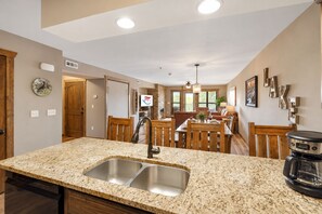 A kitchen with granite countertops, a double sink, and a coffee maker.