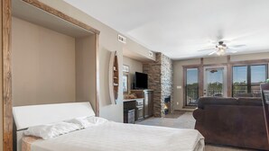 A bedroom with a bed, a television, a fireplace, and a stone wall.