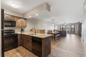 Une cuisine moderne dotée de plans de travail en granit, d’armoires en bois et d’un lave-vaisselle.