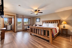 A bedroom with a wooden bed, a ceiling fan, and a view of the outdoors.