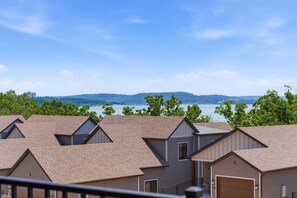 A row of residential buildings with pitched roofs, a clear view of a lake, and distant hills.