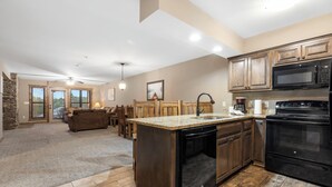 A spacious kitchen with wooden cabinets, a built-in dishwasher, and a large island with a sink. - 1 Bed, sleeps 6, Lake Access, Swim, Fish, Kayak (Branson)