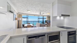 A modern kitchen with a view of the sea, a dining area with a table and chairs, and a large window.