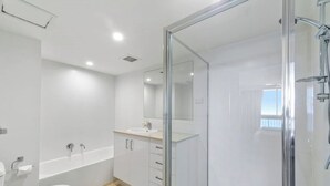 A modern bathroom with a glass shower enclosure, a white sink, and a bathtub.