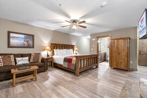 A spacious bedroom with a large bed, a wooden wardrobe, a nightstand, a desk, and a couch.