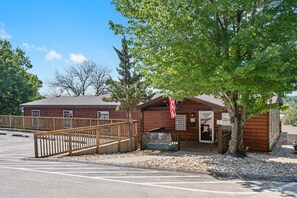 A rustic wooden building with a porch, a flag, and a bench.