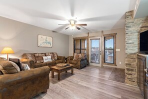 A living room with a ceiling fan, two sofas, a coffee table, and a stone fireplace.