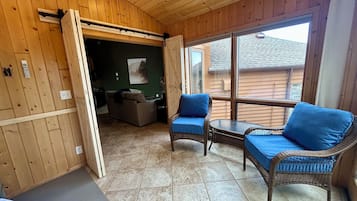 A wooden-paneled room with a dining area, a sofa, and a table with blue cushions.