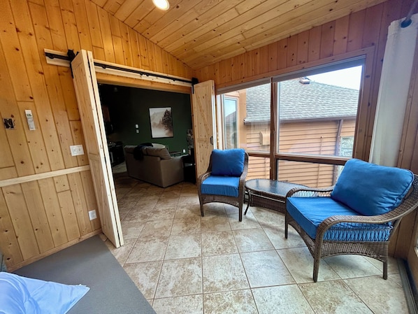 Una habitación con paneles de madera, un comedor, un sofá y una mesa con cojines azules.